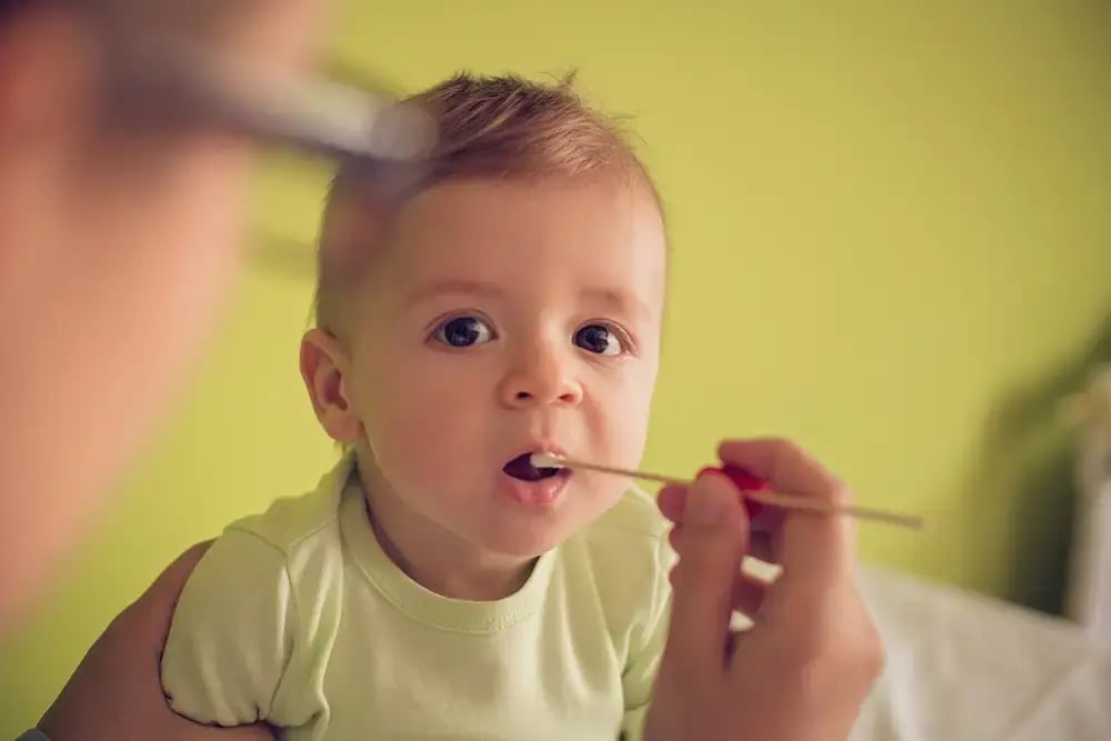 Baby with a medical swap in mouth.